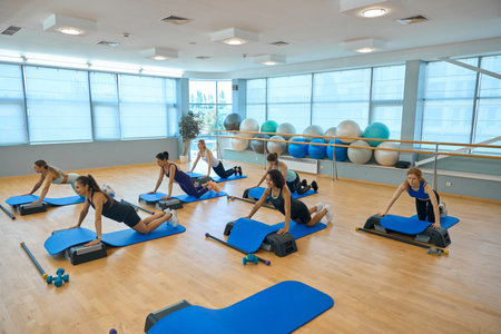 Group of women in training clothes perform strength exercisesの写真素材