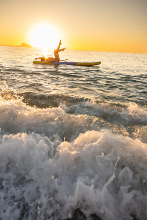 Young woman relaxing on paddleboard at ocean sunrise
