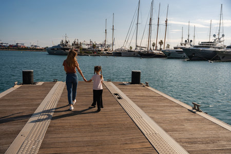 Smiling mother and little girl walking along the pier holding hands, Spain, Valenciaの写真素材