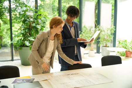 Man and woman discussing over architectural plansの写真素材