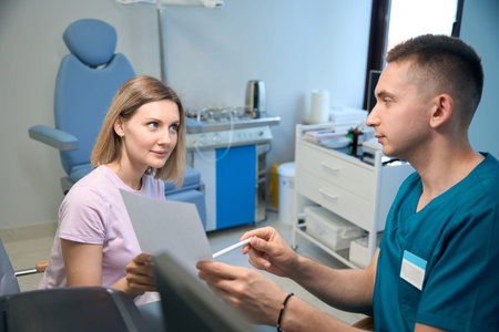 Male doctor talking and giving prescription for woman in medical office in ENT clinic