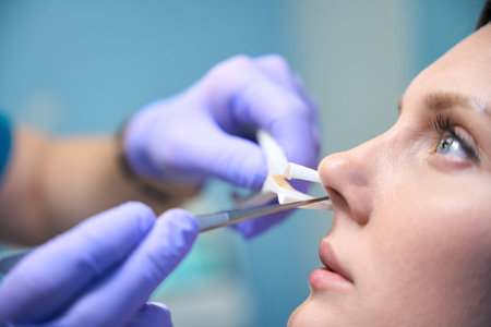 Female patient at modern ENT clinic, otorhinolaryngologist checking nose with otoscope