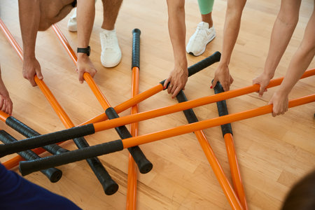 Young sporty people taking gymnastic sticks in gymの写真素材