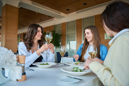 Group of female friends with wine eating in restaurantの写真素材
