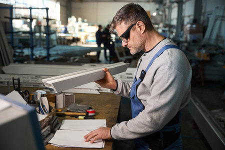 Professional production workers in coverall working with different PVC windowsの写真素材