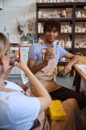 Smiling African American man holding mug in pottery studio