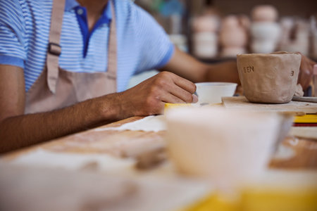 Focused adult male creating pottery in studio during daytime