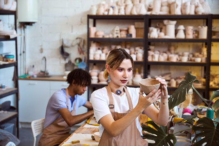 Young adults collaborating in pottery studio during daytime