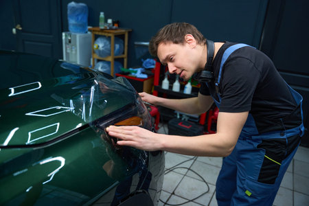 Automotive detailer is applying protective film to car tail lampの写真素材
