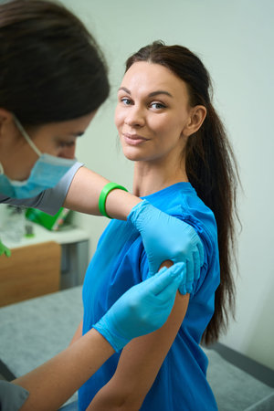 Caucasian woman receiving injection in medical room during dayの写真素材