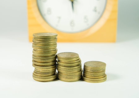 Stack of coin with clock in backgroundの写真素材