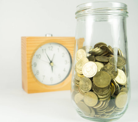 Coin in pot with clock in backgroundの写真素材