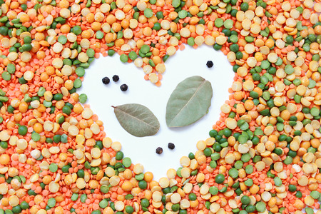 Multicolored heart frame of a mixture of peas and lentils on a white backgroundの写真素材