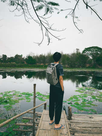 Young man backpacker stand and looking on lakeの写真素材