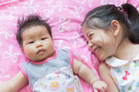 Close up Portrait of a siam cute Infant baby  girls with sisterの写真素材