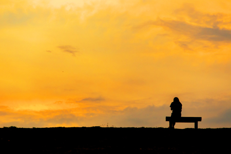 silhouette of woman relax on chair happy time sunsetの写真素材