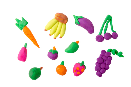 Plasticine modeling fruits orange grapes mangosteen pumpkin mango a banana strawberry carrot eggplant apple cherry blueberries together on a white plasticine backgroundの写真素材