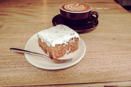 Hot Latte Coffee with Carrot Cheesecake on Wooden Table