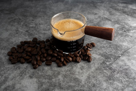 Hot coffee with roasted coffee beans on a cement floor