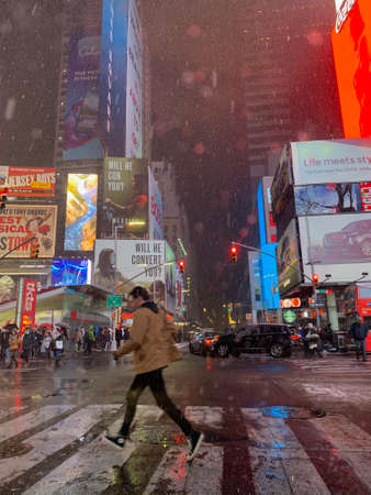 A young man runs across the road in the rain in Times Squareのeditorial素材