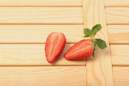 Ripe aromatic strawberries cut into two juicy halves on a wooden tableの写真素材