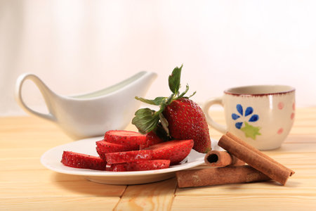 Fresh strawberries, cinnamon rolls and a cup on a wooden tableの写真素材