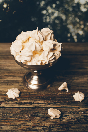 Mini meringues in silver bowl on vintage wooden tableの写真素材