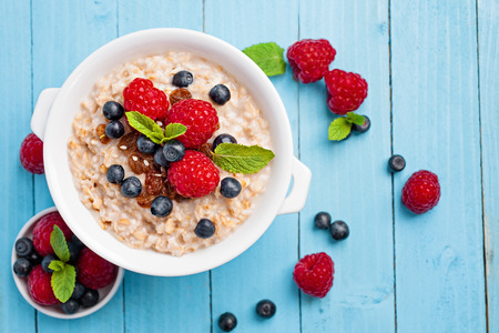 Healthy breakfast - porridge with fresh berries on blue wooden background, health and diet concept. vegetarian food.の写真素材
