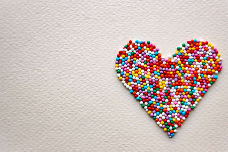 Heart from pastry sprinkles on a yellow. colorful balls