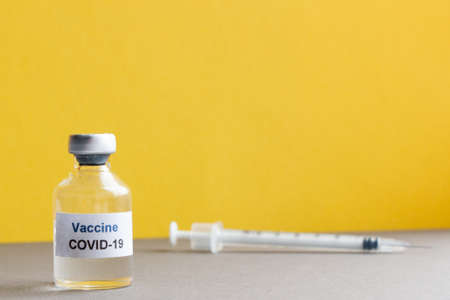 Covid-19 vaccine on yellow, gray backgroundの写真素材