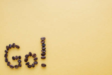 Word GO from coffee beans on a yellow background.