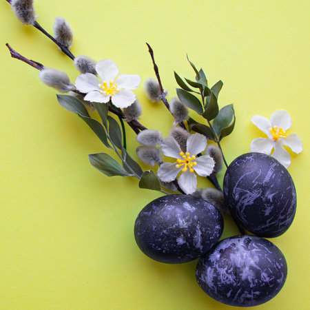 Easter eggs in blue lie on a yellow background. Space colored eggs. Flowers