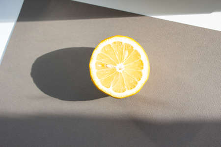 half of a whole lemon lies on a gray background. Sunlight feeds lemonの写真素材
