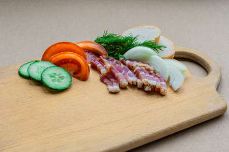 Lard onion tomatoes cucumber, dill on a wooden plankの写真素材