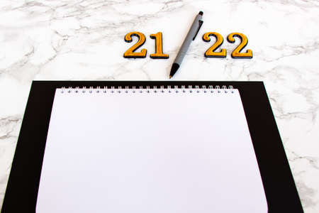 notebook with a blank sheet, a pen for writing plans for 2022. number 2022の写真素材