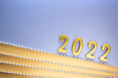 2022 New years number is laid out in wooden numbers on a silver and yellow backgrounds next to silver Christmas beadsの写真素材