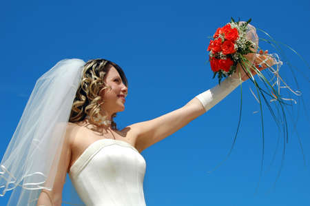 The happy bride with a bouquet of roses on a background of the sky