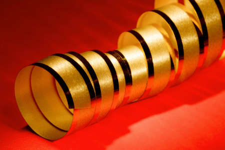 Golden curly ribbon on red backgroundの写真素材