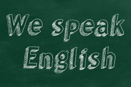 Hand drawing "We speak English" on green chalkboardの写真素材
