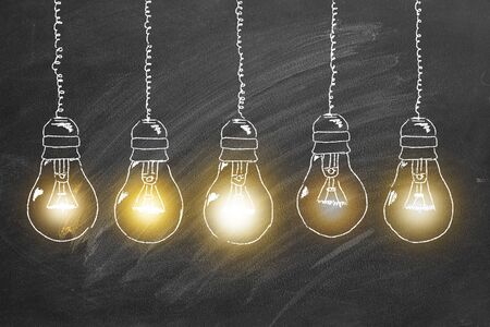 Row of  tungsten light bulbs drawn in chalk on a blackboard. Concept of brainstorming  process.の写真素材