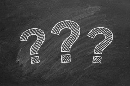Three question marks drawn in chalk on a blackboard.
