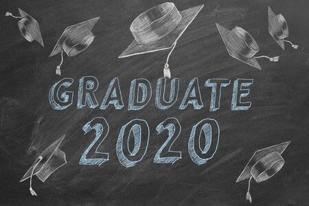 Hand drawing Graduate 2020 and graduation caps on blackboard