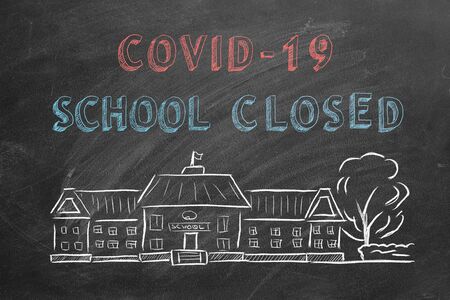 School building  and lettering COVID-19 School closed on blackboard. Hand drawn sketch. Coronavirus concept.の写真素材