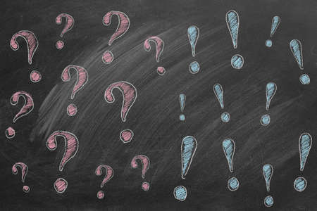 Hand drawn question marks on the left and exclamation marks on the right. Illustration are drawn in chalk on a blackboard. FAQ or discussion concept.の写真素材