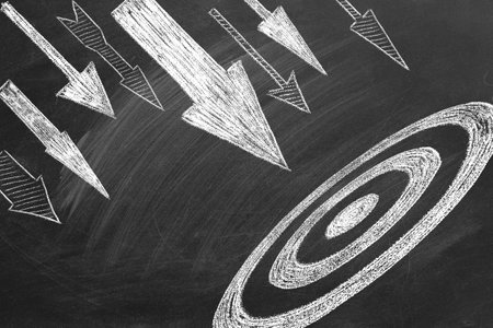 Many different arrows and target drawn in chalk on a blackboard. Concept of competition, strategy,...