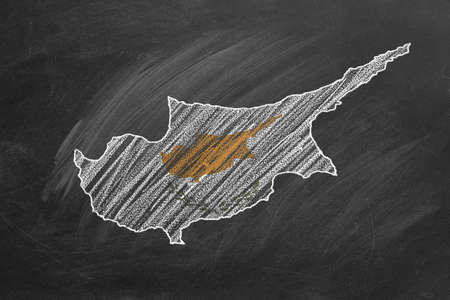Country map and flag of Cyprus drawing with chalk on a blackboard. One of a large series of maps and flags of different countries. Education, travel, study abroad concept.の写真素材