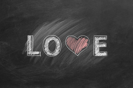LOVE word with heart shape hand drawn on blackboard. Valentines day, love, compassion concept.の写真素材