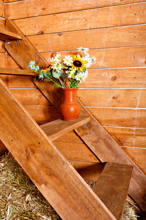 Vase with different flowers bouquet on the stairs with wooden backgroundの写真素材