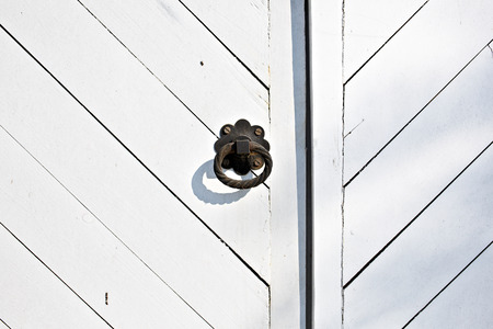 Black metal door knob on the white wooden door with grunge texture. Mediterranean style.の写真素材