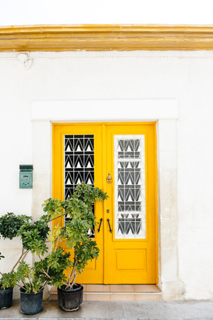 The classical architecture of the Mediterranean (Greece, Italy, Spain, Cyprus, Portugal).  Wooden yellow door on the white buildings and plants. Postal box.のeditorial素材